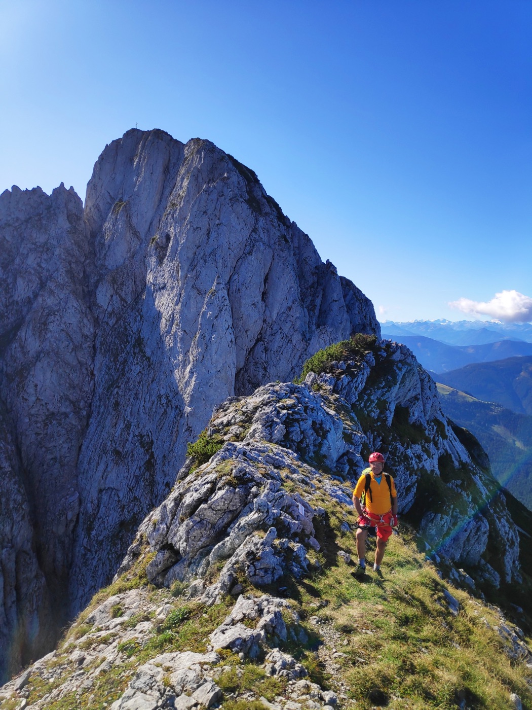 Bergsteiger am Grat mit Blick auf das Gipfelkreuz des Donnerkogels