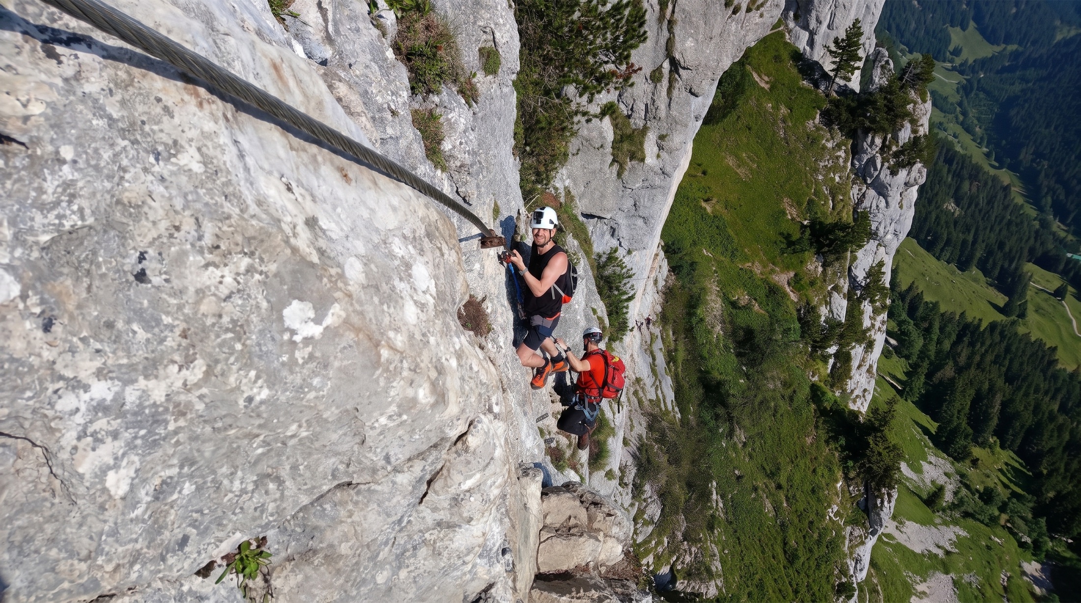 Zwei Klettersteiggeher in der senkrechten Wand des Donnerkogels hoch über dem Tal